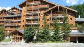 A multi-story wooden building with balconies, likely a hotel or resort. - 200m from ski slopes, 6th floor, swimming pool, tv, ski locker, 50m², Méribel (Méribel - Les Allues)
