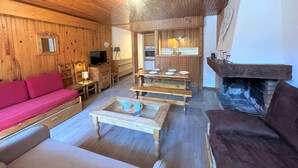 A wooden interior with a sofa, coffee table, and fireplace.