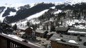 A snow-covered mountain town with buildings, including a pub, and a ski slope in the background.