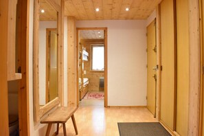 Un intérieur en bois avec un banc, une porte et une vue sur une autre pièce.