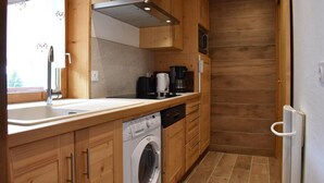 A compact kitchen with wooden cabinets, a built-in washing machine, a coffee maker, and a microwave. - Ski-in/ski-out & foot of the slopes, balcony, tv, ski locker, 105m², Méribel (Méribel - Les Allues)