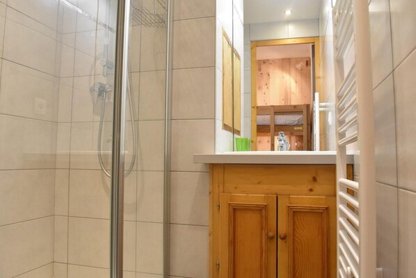 A bathroom with a glass shower enclosure, wooden cabinets, and a white countertop. - 150m from ski slopes, 2nd floor, tv, 24m², Méribel (Méribel - Les Allues)