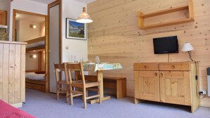 A wooden interior with bunk beds, a dining table with chairs, a television, and a cabinet. - 100m from resort center, 2nd floor, tv, 24m², Méribel (Méribel - Les Allues)