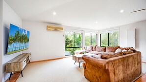 A modern living room with a large brown leather sofa, a wooden coffee table, and a painting of a beach scene.
