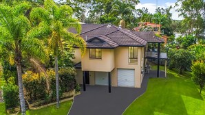 A two-story house with a tiled roof, a garage, and a well-maintained lawn.