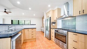 A modern kitchen with a gas stove, oven, refrigerator, and wooden cabinets.