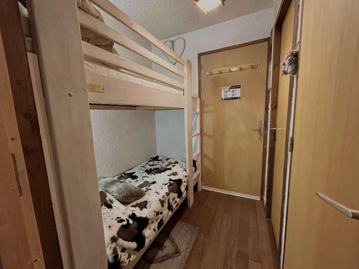 Ein Etagenbett mit Kuhmuster-Matratze in einem Raum mit Holzboden und Holztür.