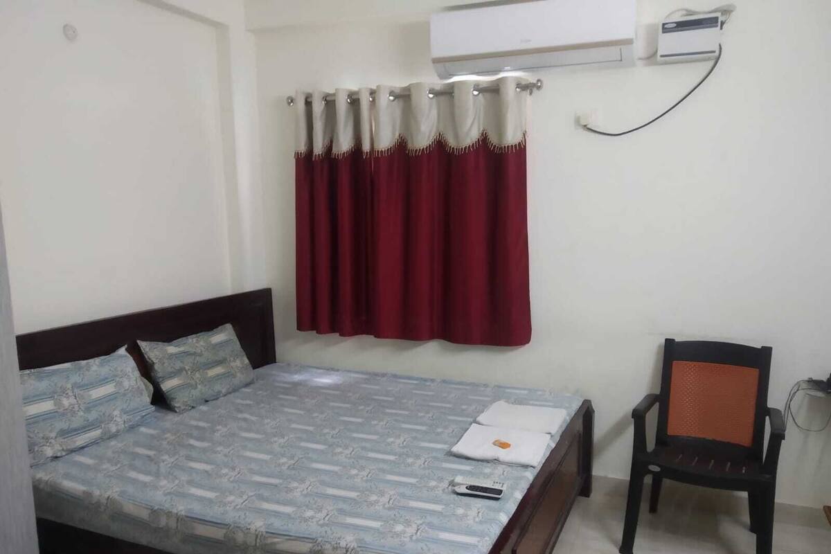 Een slaapkamer met een bed, een stoel en een airconditioning aan de muur.
