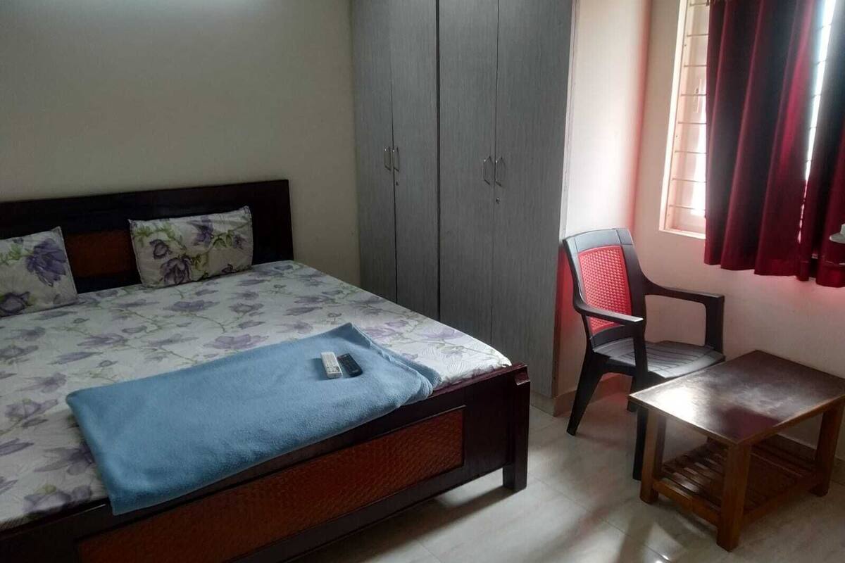 Een slaapkamer met een bed, een kledingkast, een bureau en een stoel.