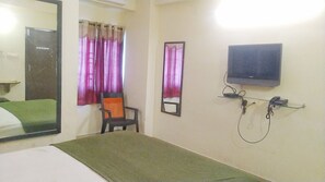 A hotel room with a bed, a chair, a television, and a mirror.