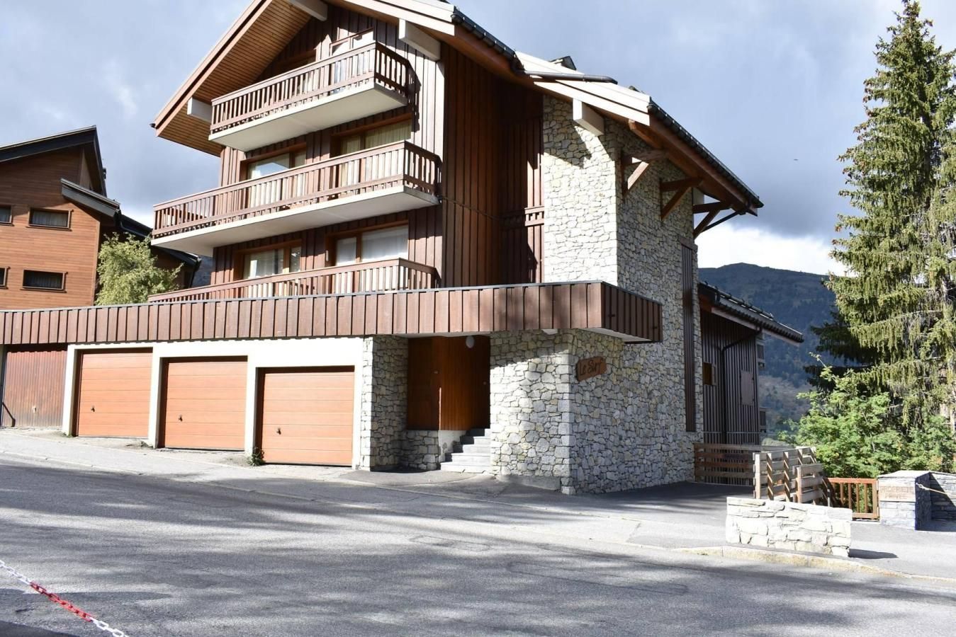 A multi-story building with a stone facade, wooden balconies, and a garage entrance.