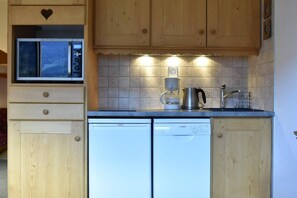 A kitchen with wooden cabinets, a Bosch dishwasher, a coffee maker, and a microwave.