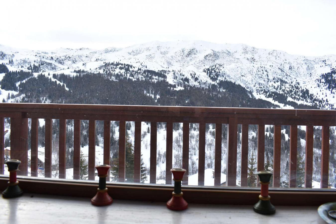 Une balustrade en bois donnant sur un balcon, avec vue sur des montagnes et des arbres couverts de neige.