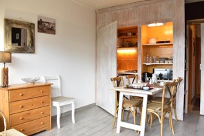 A compact living space with a dining area, a small kitchenette, and a wooden dresser.