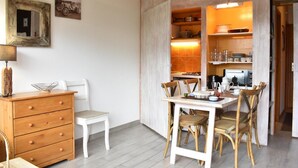 A compact living space with a dining area, a small kitchenette, and a wooden dresser.
