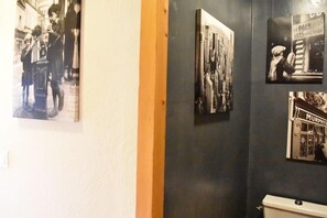 Three black and white photographs adorn the wall, showcasing a city scene, a bustling street, and a local storefront.