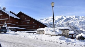 A snow-covered building with a stone wall and a street lamp.