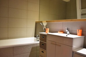 Un baño moderno con bañera, lavabo con espejo y tocador con cajones.