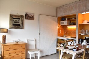 Cocina compacta con comedor, que incluye un armario blanco, un microondas y un salpicadero de azulejos.