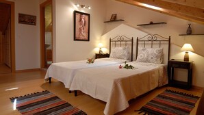Ein Schlafzimmer mit zwei Betten, Holzböden, einer geneigten Decke und Nachttischlampen.