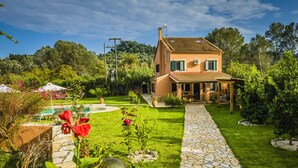 Ein Haus mit einem Kiesweg, der zu einer Tür führt, umgeben von einem gepflegten Garten und einem Poolbereich.