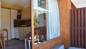 Une cuisine compacte avec des meubles en bois, un four à micro-ondes et un coin repas comprenant une table et des chaises.