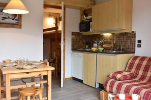 Une cuisine compacte avec un coin repas, un four à micro-ondes et un canapé.