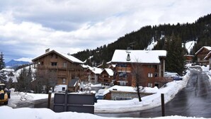 Un village de montagne enneigé, avec des bâtiments en bois et une route qui monte vers le sommet.