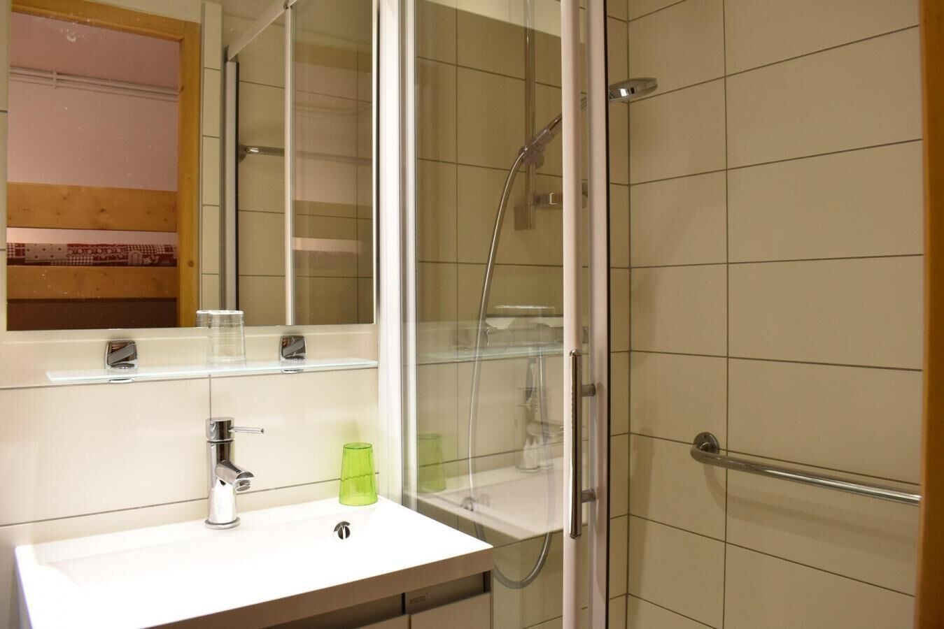 Un baño moderno con cabina de ducha de vidrio, un lavamanos blanco y un espejo encima.