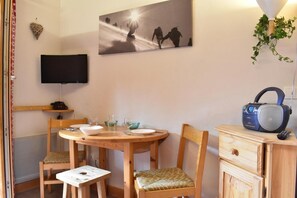 A cozy room with a round wooden table, two chairs, a small TV, a radio, and a wall-mounted picture. - 300m from shops, 1st floor, balcony, tv, ski locker, 18m², Méribel (Méribel - Les Allues)