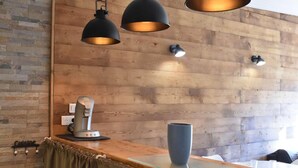 A modern kitchen with wooden walls, a coffee machine, and pendant lighting.