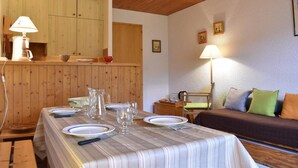Un comedor con una mesa dispuesta para cuatro, un armario de madera, un sofá con cojines y una lámpara.