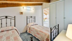 Ein Schlafzimmer mit zwei Betten, Holzbalken an der Decke, einem Nachttisch und einem Kleiderschrank.