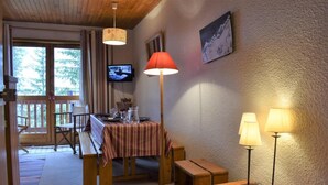 Una habitación acogedora con una mesa de madera preparada para comer, un banco y un televisor en la pared.