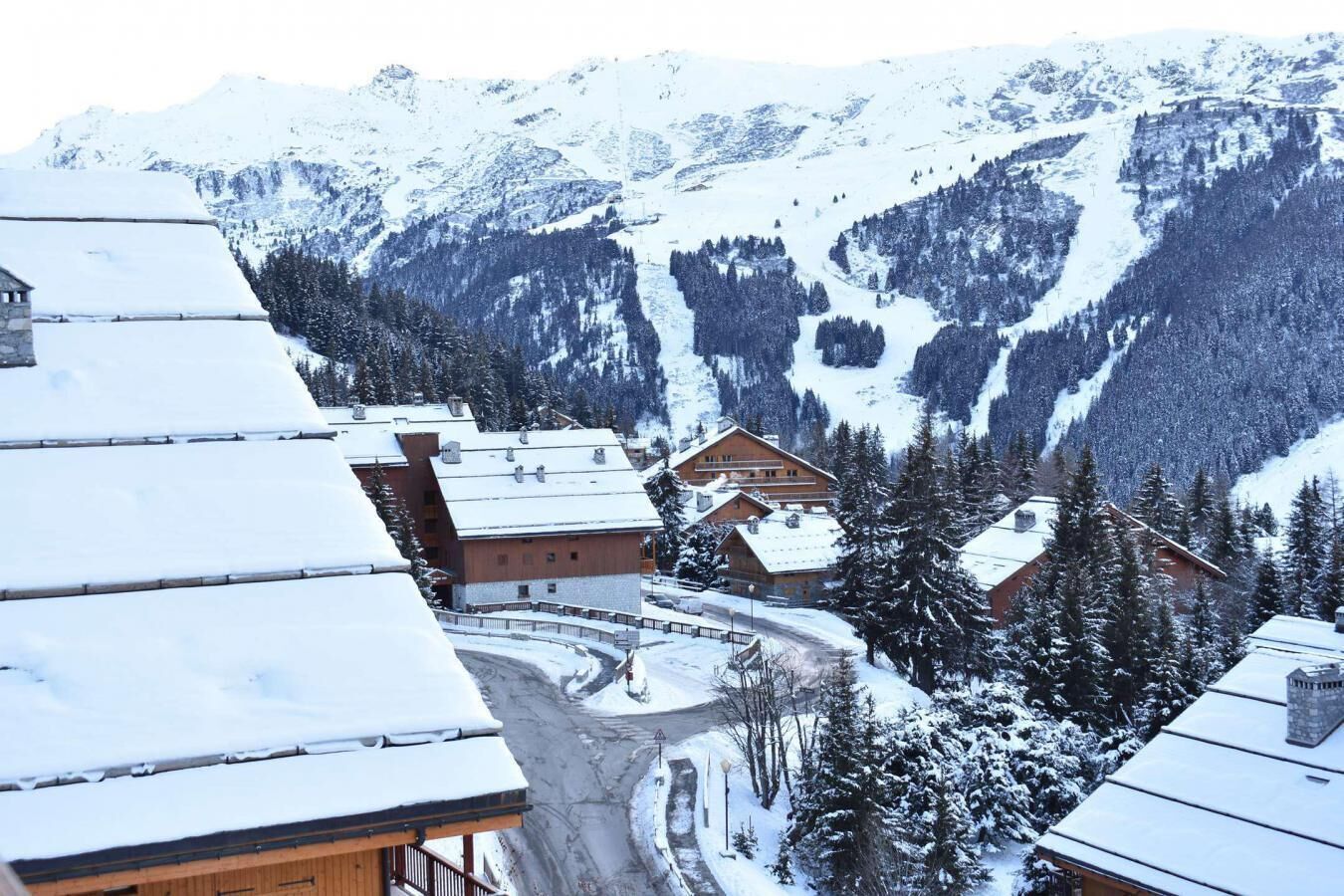 A snow-covered mountain village with wooden buildings and a winding road.