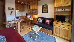 Ein gemütlicher Wohnbereich mit einer Couch, einem Esstisch und einer Küche im Hintergrund.