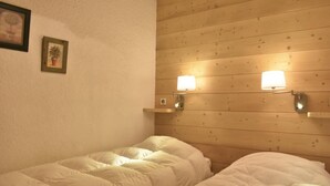 Ein Zimmer mit zwei Betten, Holzwandverkleidung und Wandleuchten.