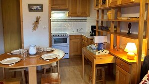 Eine gemütliche Küche mit Holzschränken, einem Herd und einem Esstisch für vier Personen.