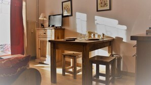 Une pièce chaleureuse avec une table en bois, un téléviseur et une fenêtre avec des rideaux.