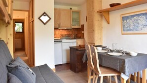 A cozy kitchen with wooden cabinets, a dining table set for two, and a view of the mountains through the window. - 100m from ski slopes, 3rd floor, balcony, tv, 28m², Méribel (Méribel - Les Allues)