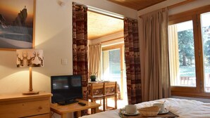 A bedroom with a bed, a TV, a dresser, a window with curtains, and a painting on the wall. - 150m from shops, Ground floor, terrace, ski locker, 40m², Méribel (Méribel - Les Allues)
