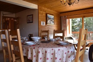 Zona pranzo con sedie di legno e un tavolo apparecchiato per quattro, con tovaglia decorata con cuori e fiocchi di neve.