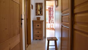 A narrow hallway with wooden doors and a small stool. A wooden cabinet with heart-shaped handles is visible. - 100m from ski slopes, 2nd floor, balcony, ski locker, 60m², Méribel (Méribel - Les Allues)