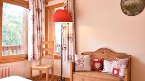 A cozy room with a wooden bed, a chair, a red floor lamp, and a window with curtains. - 100m from ski slopes, 2nd floor, balcony, ski locker, 60m², Méribel (Méribel - Les Allues)