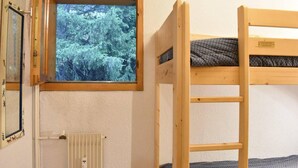 A bunk bed with a window overlooking a forest.