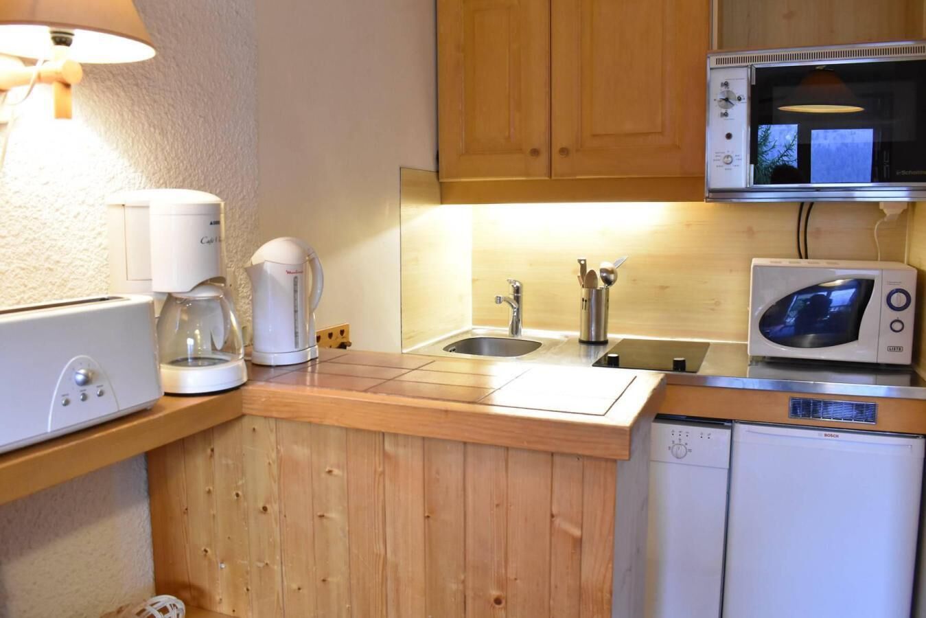 Una kitchenette compacta con cafetera, microondas y fregadero.