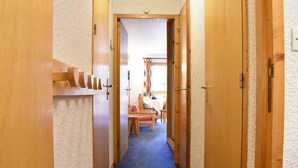 A narrow hallway with wooden doors on either side, carpeted floor, and a dining area visible in the background. - 200m from shops, 1st floor, view mountain, balcony, ski locker, 28m², Méribel (Méribel - Les Allues)