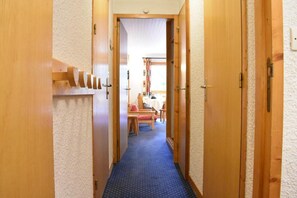 A narrow hallway with wooden doors on either side, carpeted floor, and a dining area visible in the background. - 200m from shops, 1st floor, view mountain, balcony, ski locker, 28m², Méribel (Méribel - Les Allues)