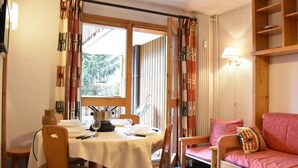 A cozy room with a dining table set for two, a sofa, and a window with curtains. - 200m from shops, 1st floor, view mountain, balcony, ski locker, 28m², Méribel (Méribel - Les Allues)