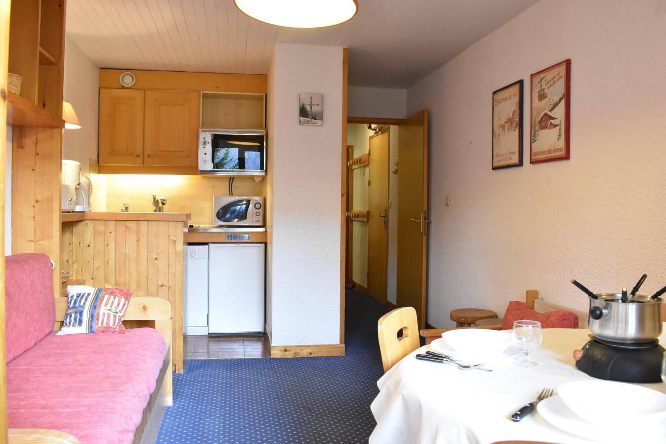 Kompakti huone, jossa on pieni keittiönurkkaus, ruokailutila ja pieni oleskelualue.